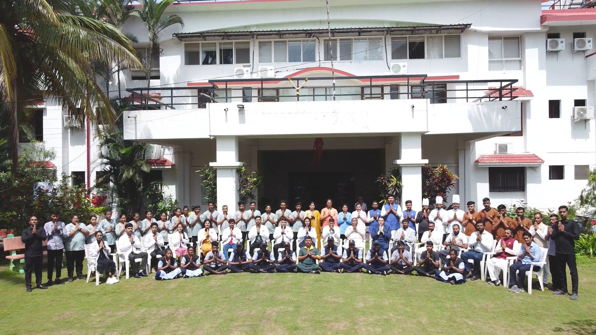 Staff and therapists of Atmabodh Wellness Center standing together with folded hands on the lawn in front of the building