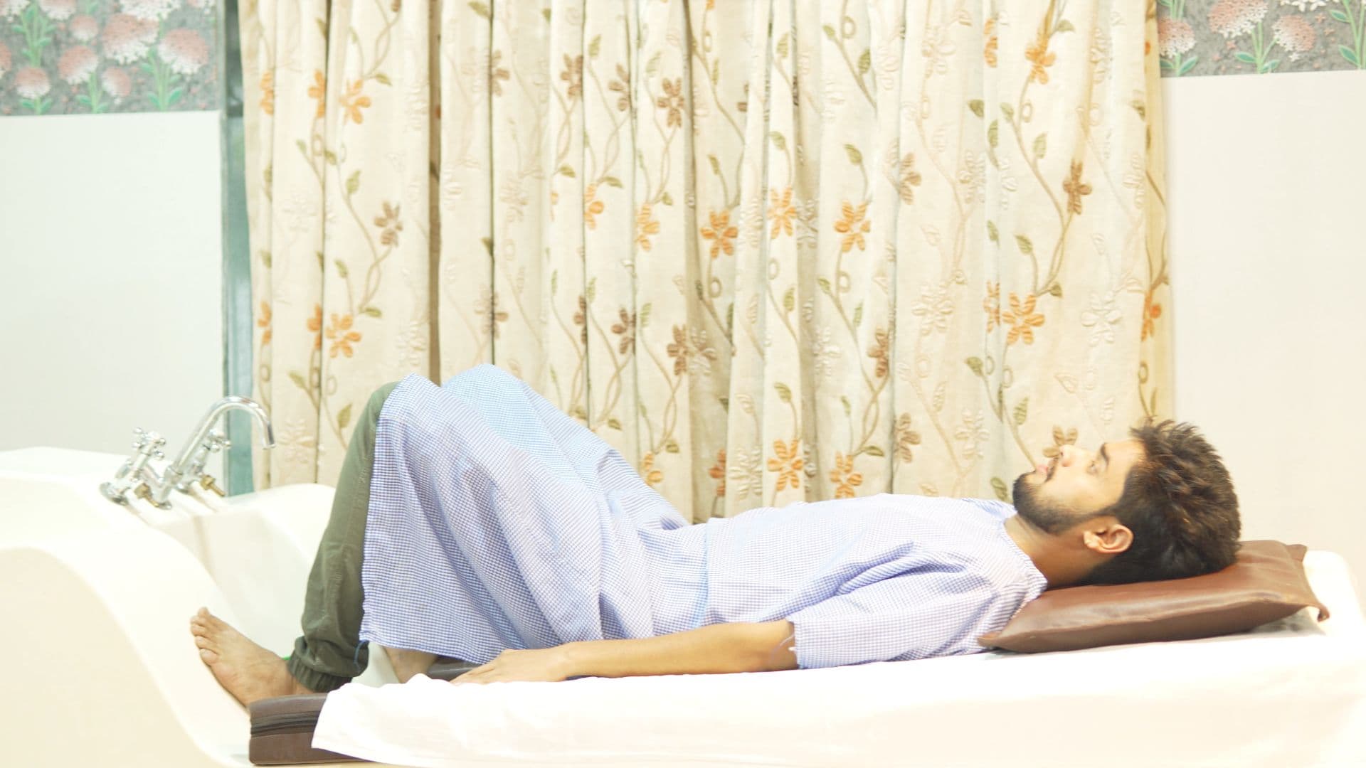 A client resting on a hydrotherapy table in a naturopathy therapy room at Atmabodh Wellness Center