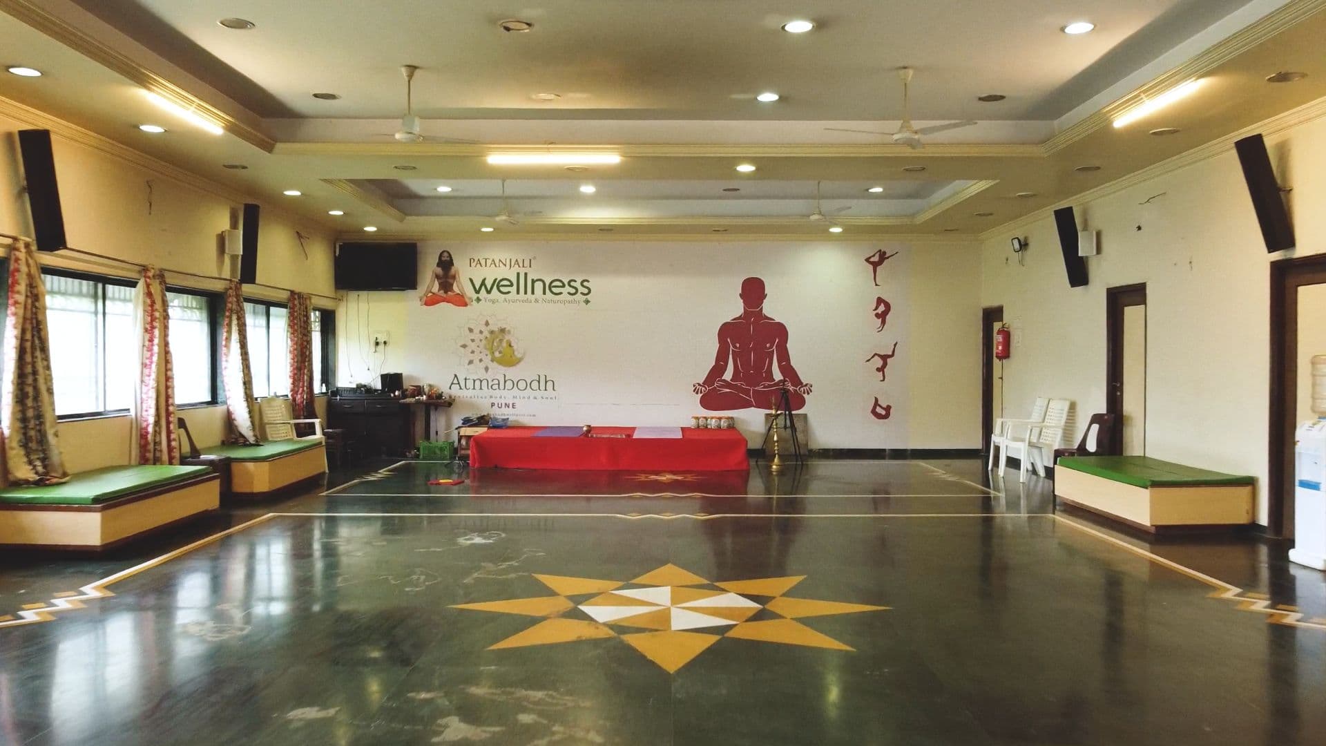 The yoga and training hall at Atmabodh Wellness Center with a polished floor and a raised platform